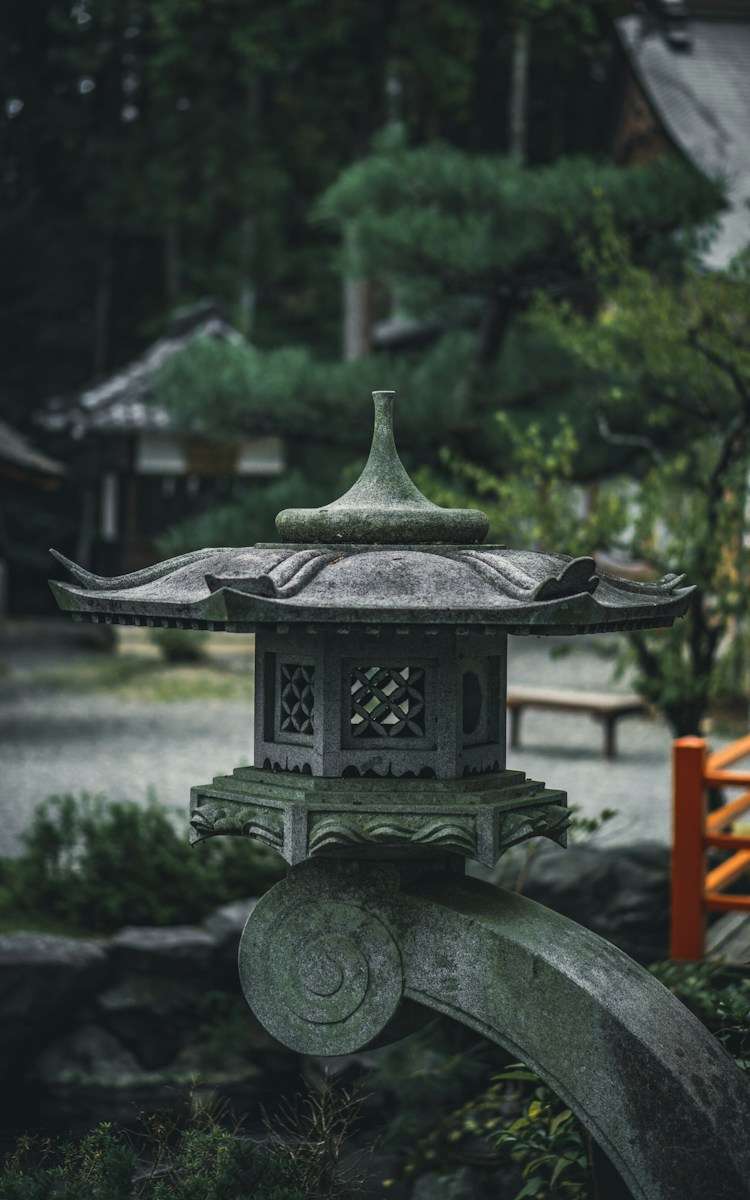 a stone lantern in a park with trees in the background