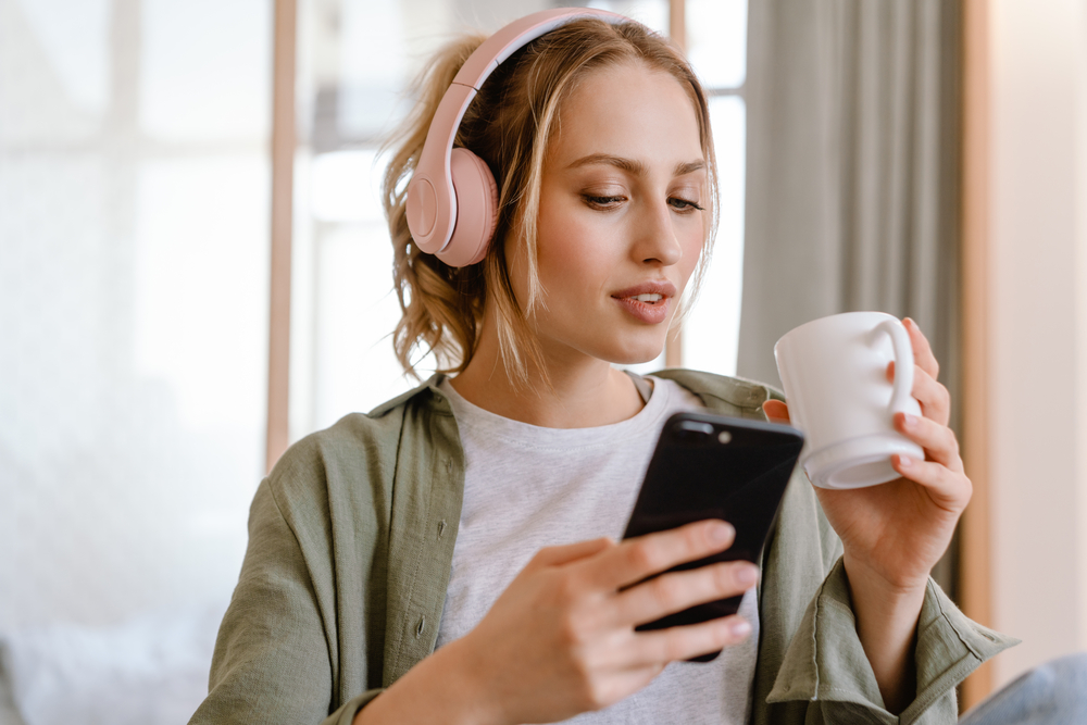 Woman listeting to music on phone while drinking coffee.png