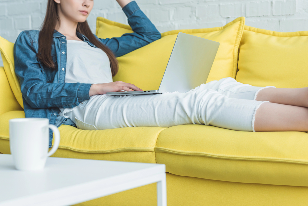 Woman sitting on her sofa looking at her laptop reading a User Interviews Review.png
