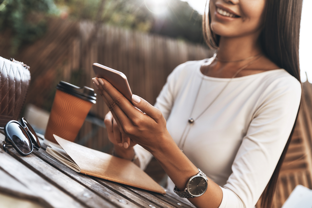 Woman taking paid surevys on smartphone drinking coffee.png
