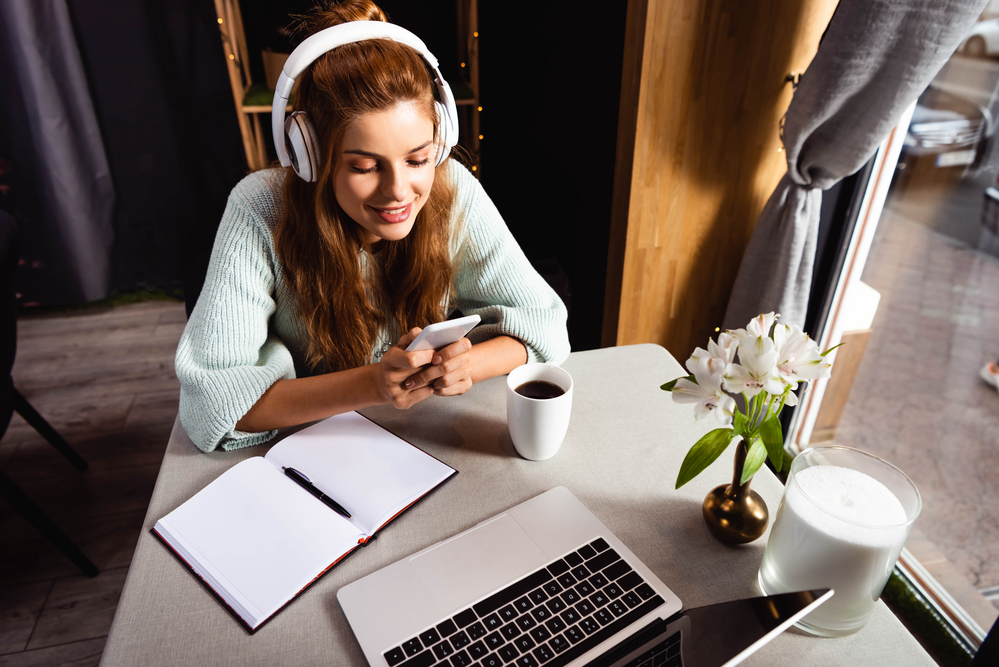 Woman wearing headphones reading an Appen review on her smartphone.png