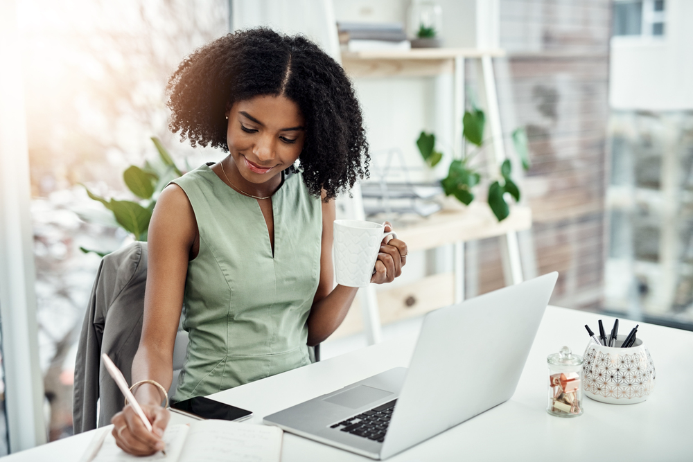 Young black woman writing in a notebook taking a free online course.png