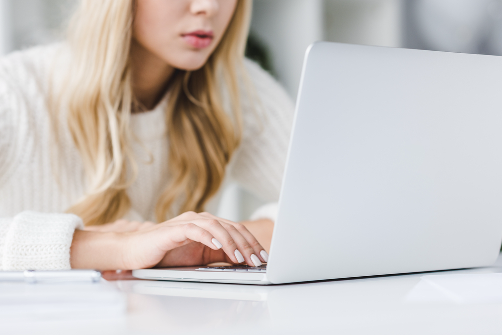 Young blonde woman searching for remote retail jobs on her laptop.png