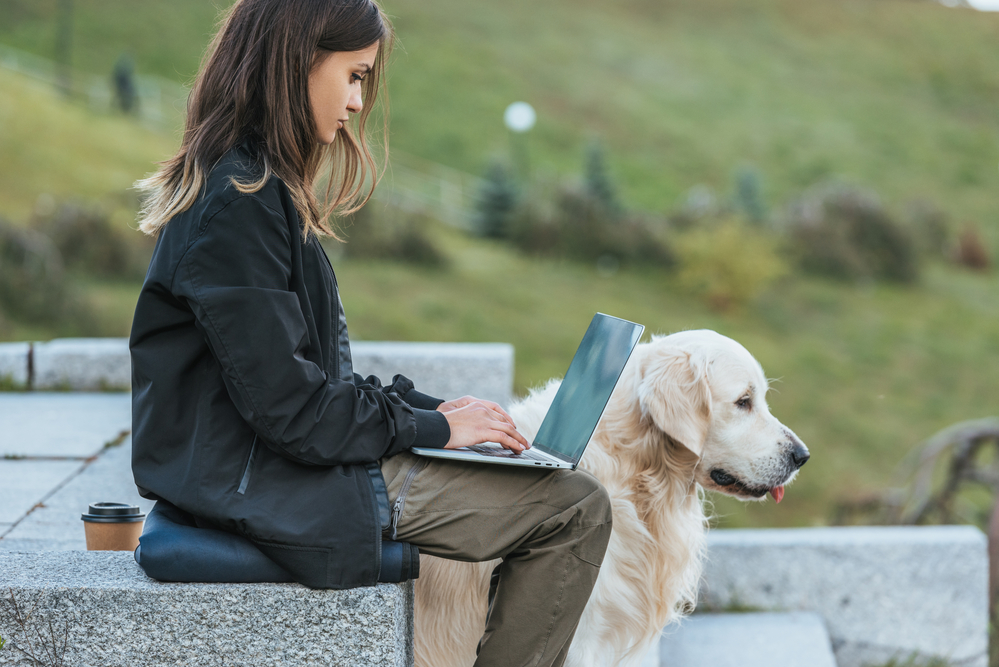 Young woman outside working on the weekend on her laptop wit her dog .png