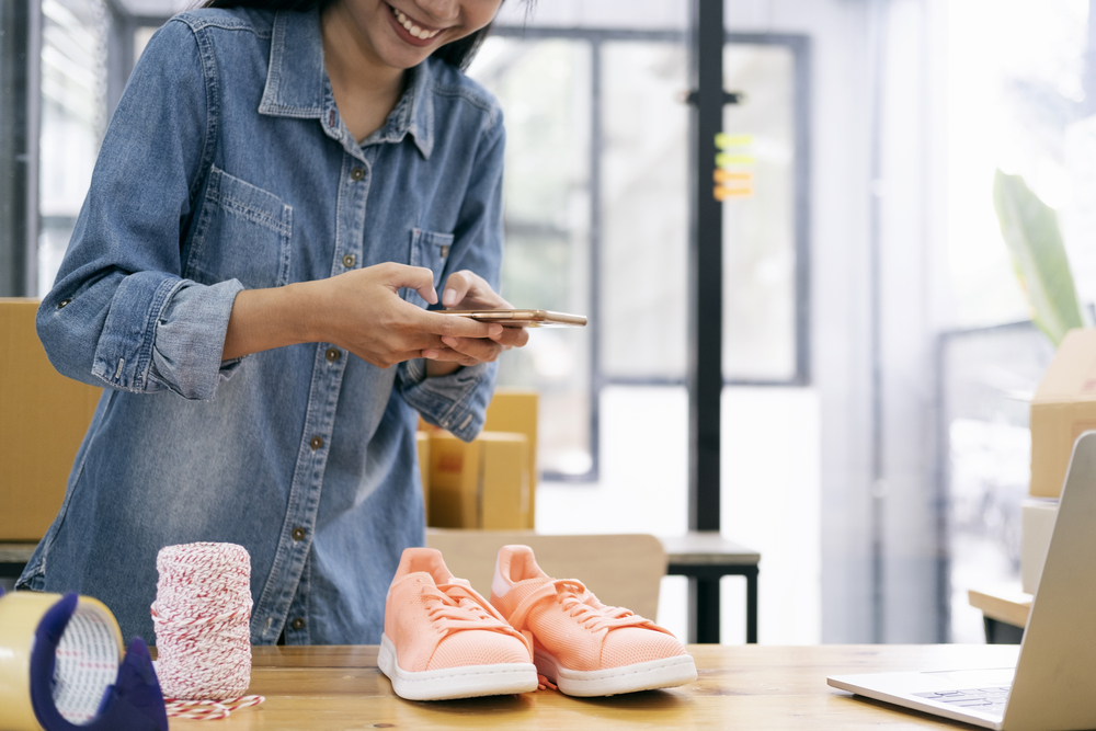 Young woman taking a photo of shoes she is selling online.png