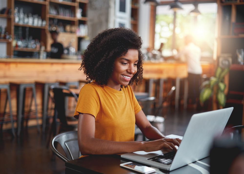 Young woman typing on laptop for her job for blog post get paid weekly.png