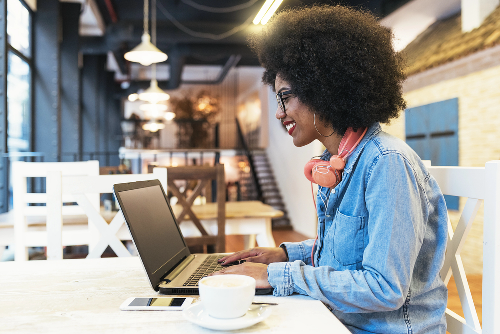 Young woman working in a cafe on her laptop as a search engine evaluator.png