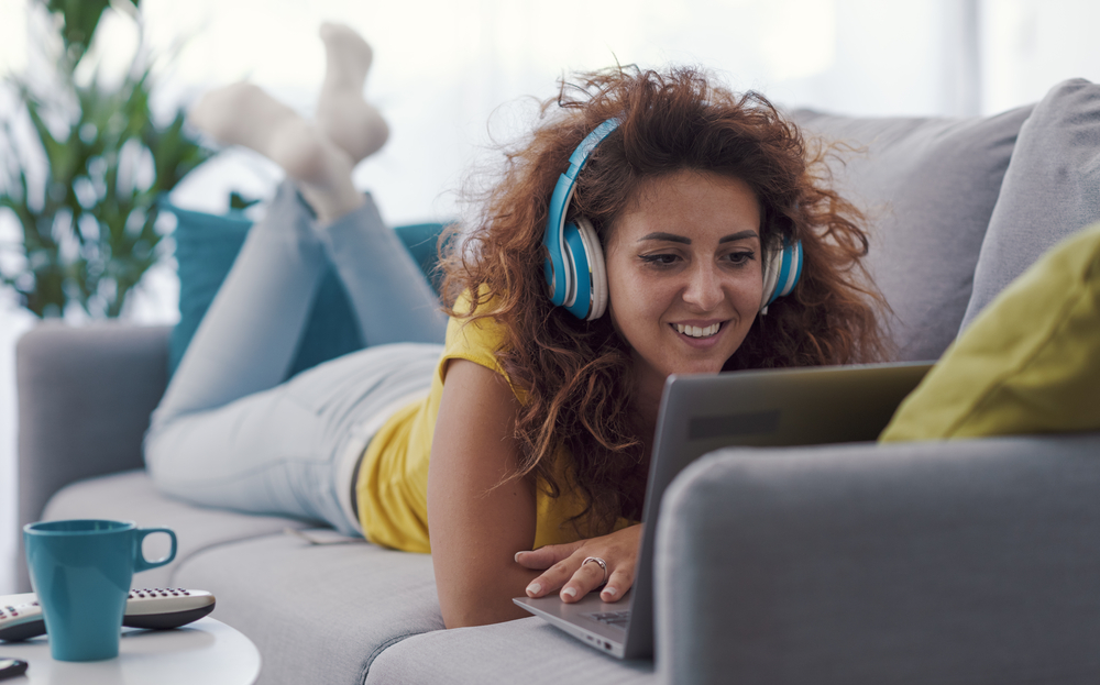 woman laying on her belly on the sofa making money watching vidoes on her laptop.png