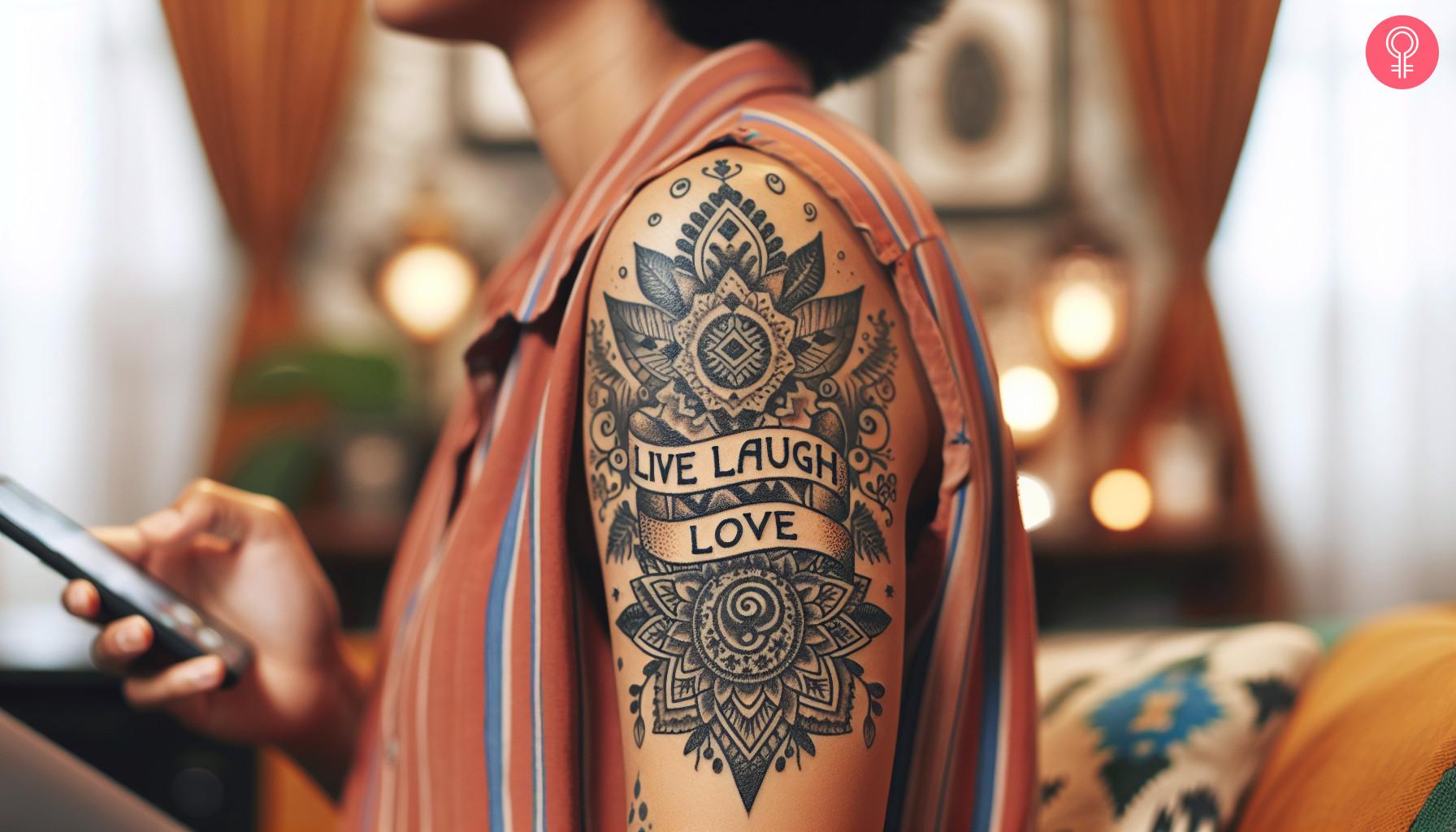 A woman with a black live laugh love tattoo on her upper arm.jpg