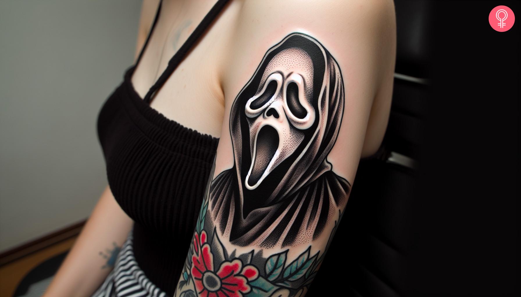 A woman with a ghost face tattoo on her upper arm.jpg