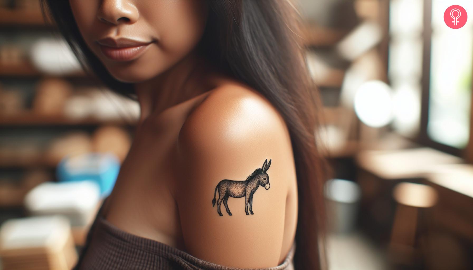 A woman with a minimalist black donkey tattoo on her upper arm.jpg