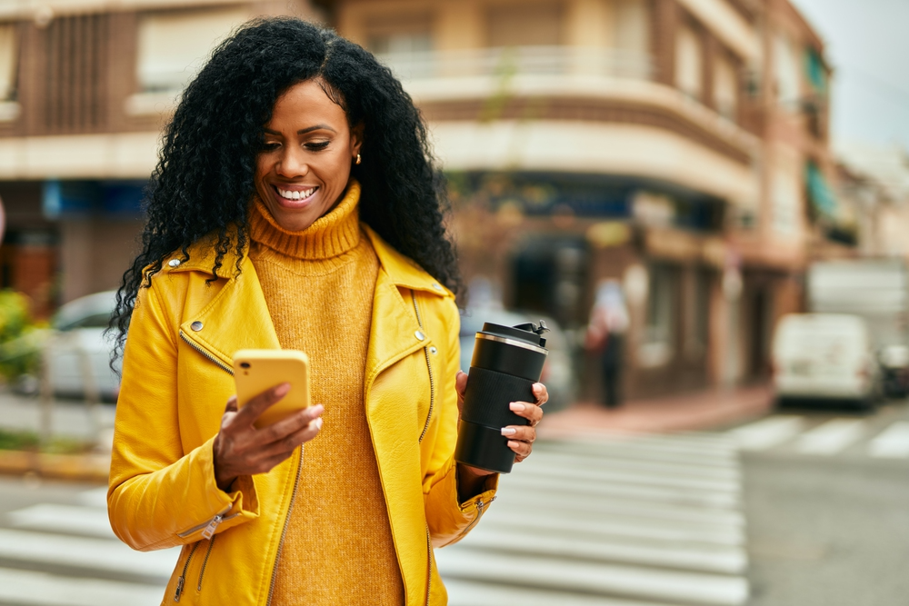 Woman drinking coffee and reading a Gigwalk review on her phone.png