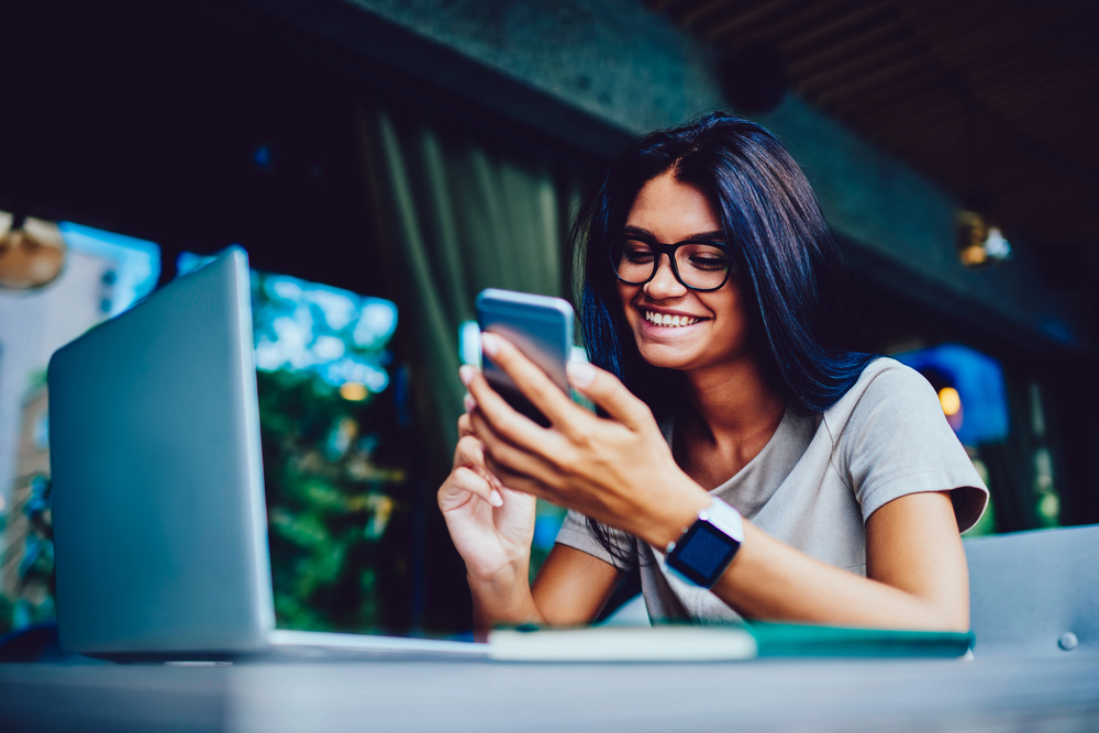 A young woman looking at her phone wanting to earn money watching videos online.png