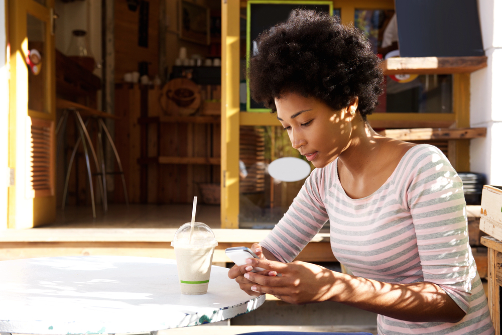 Woman sitting at a cafe using apps to make real cash.png