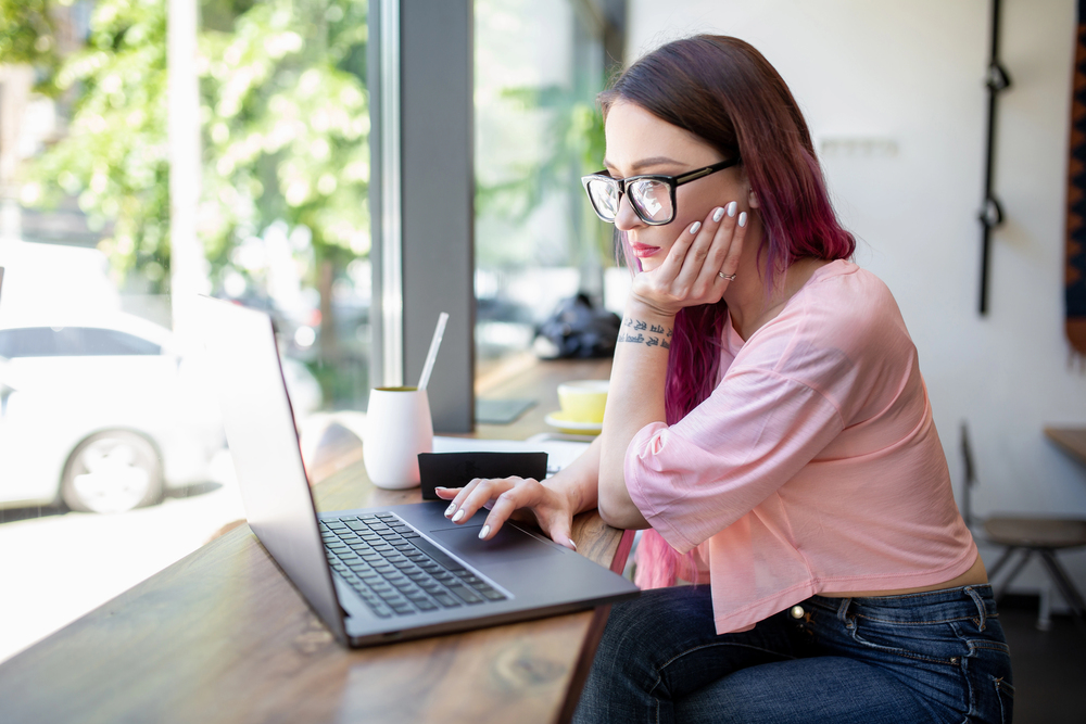 A woman wearing glasses reading a CrowdGen by Appen review on her laptop.jpeg