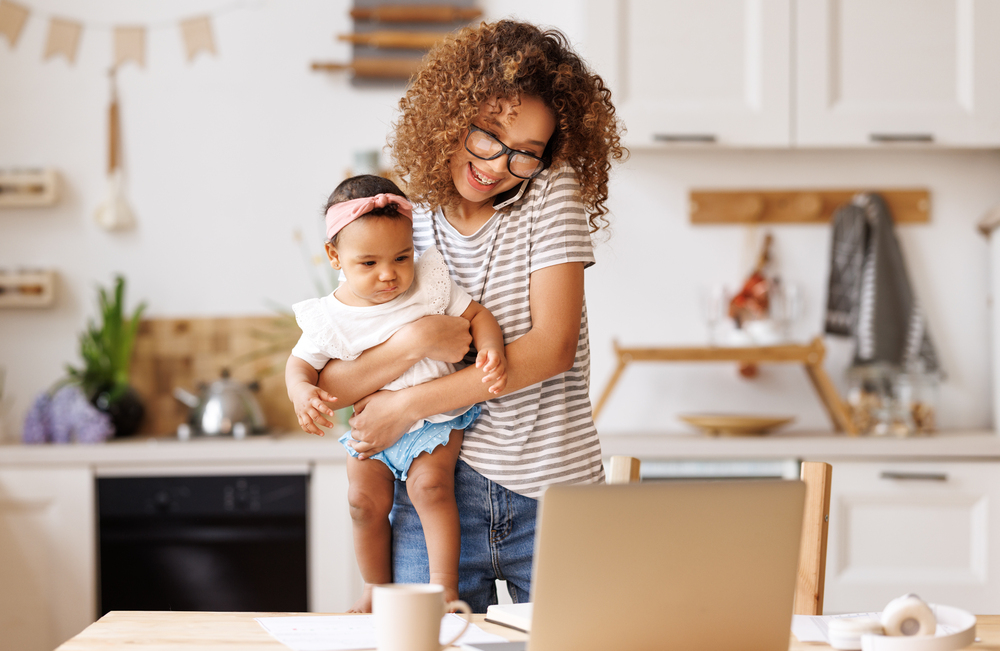 Mom holding a baby looking for easy work from home jobs on her laptop.jpeg