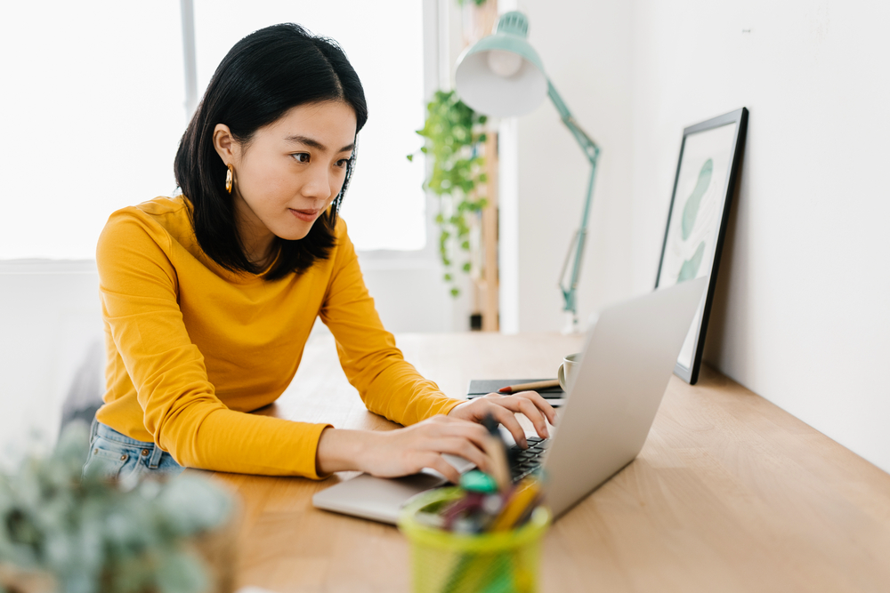 Young Asian woman working from home at her low stress job.png
